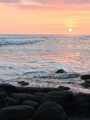 A coastal sunset with waves and rocks.