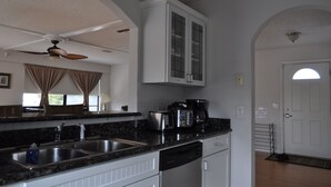 Una cocina con encimeras de granito, lavavajillas, cafetera y ventilador de techo.