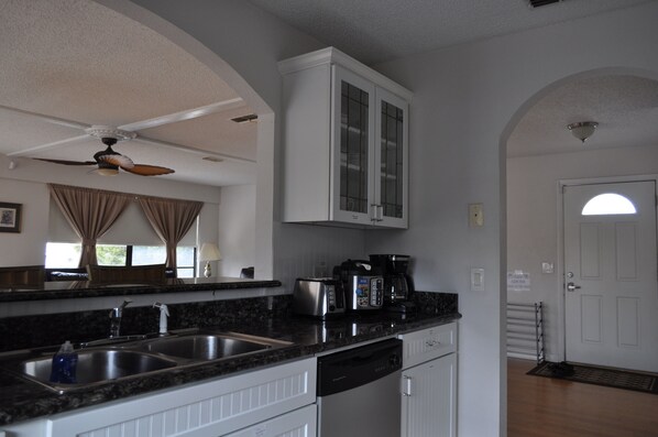 A kitchen with granite countertops, a dishwasher, a coffee maker, and a ceiling fan.
