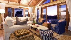 A cozy living room with a wooden ceiling, large windows, and comfortable seating.