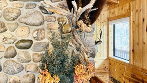 A bear statue on a wooden structure with a stone wall background and a window.