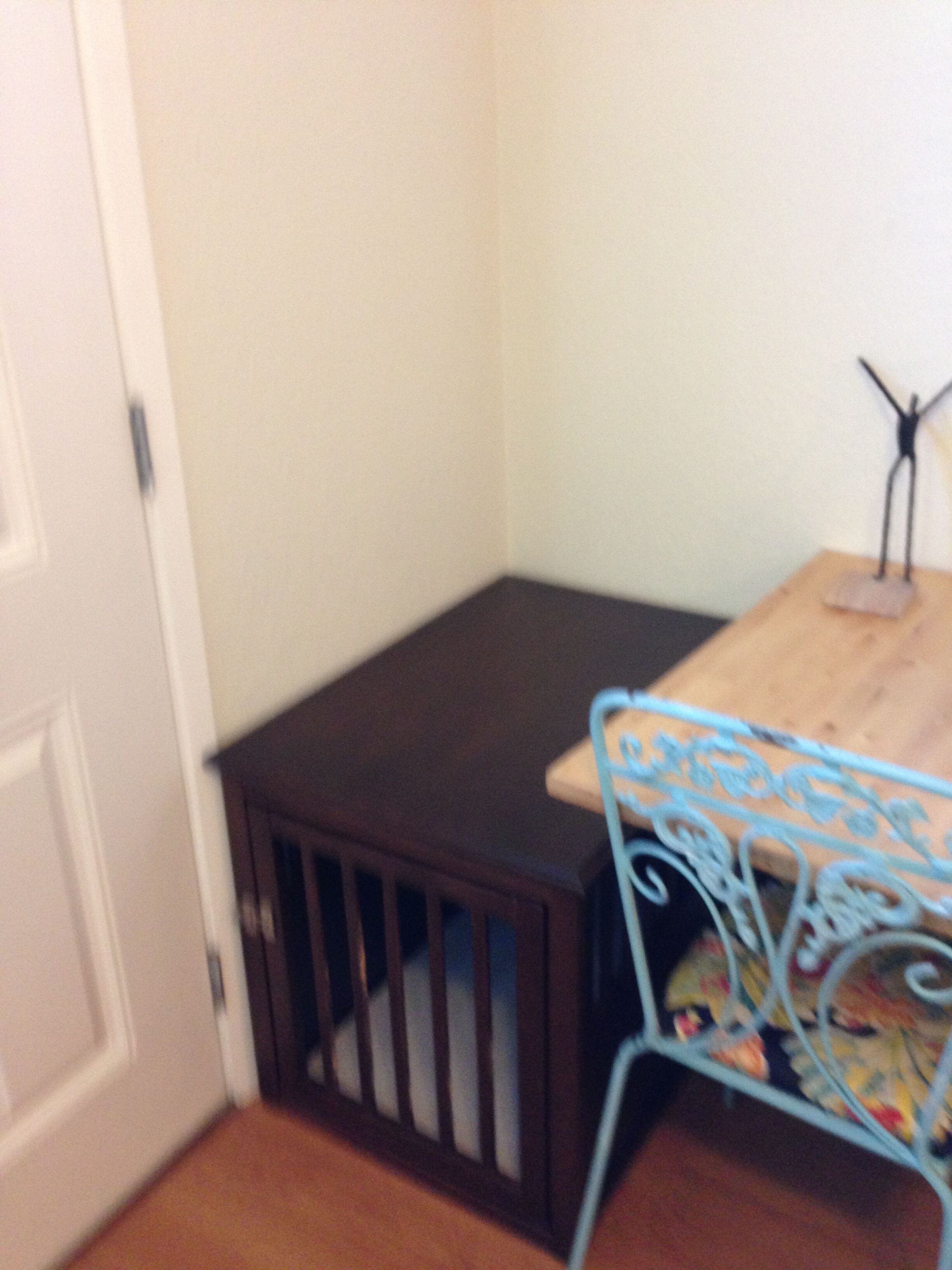 A corner of a room with a wooden table, a blue metal chair, and a small wooden cabinet.
