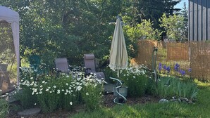 Ein Garten mit Terrasse, Gartenmöbeln und einer Pergola.