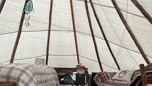 Ein gemütliches Zeltinnere mit einem Bett, einem Schlafbereich und einem kleinen Tisch.