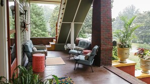 A covered porch with two chairs, a small table, and a red cylindrical stool. - Bear House 1890, Johnson Retreat, Mins from Downtown, Perfect Luxurious Getaway! (Chattanooga)