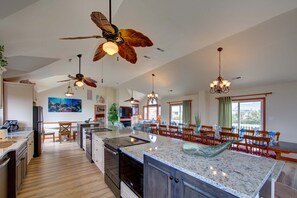 A spacious kitchen with granite countertops, a central island, and a dining area with wooden chairs.