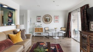 A living room with a sofa, two chairs, a coffee table, a TV, and a window with curtains.