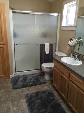 Une salle de bain avec une douche en verre, des toilettes, un lavabo avec un miroir et des meubles en bois.