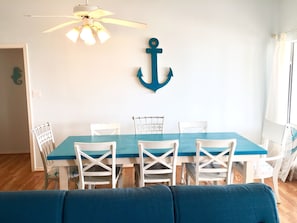 A dining area with a table and chairs, a ceiling fan, and a wall-mounted anchor decoration.