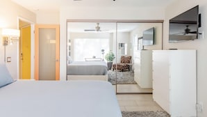 A bedroom with a bed, a desk, a chair, a TV, and a sliding door leading to another room. - Modern Palm Springs Retreat • Resort Pool + Hot Tub • Quiet & Central Location (Palm Springs)