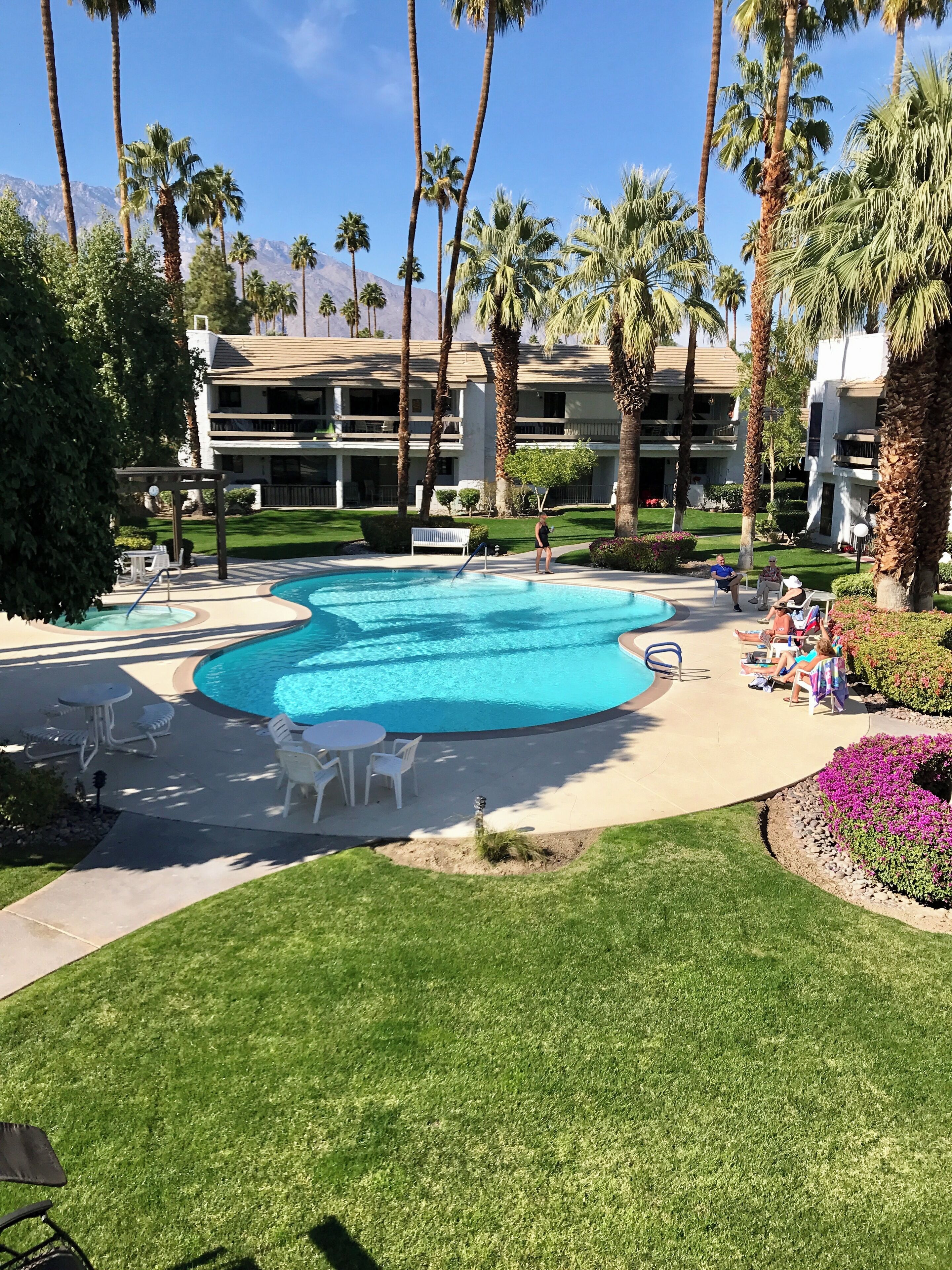 Ein Resort mit großem Schwimmbad, Palmen und einem mehrstöckigen Gebäude mit Balkonen.