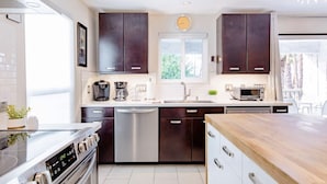 A modern kitchen with dark cabinets, stainless steel appliances, and a wooden countertop. - Modern Palm Springs Retreat • Resort Pool + Hot Tub • Quiet & Central Location (Palm Springs)