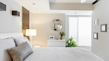 A modern bedroom with a large bed, bedside table, lamp, and a mirror on the wall.