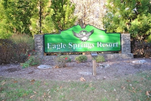 A sign for Eagle Springs Resort with a bird emblem and a stone wall backdrop.