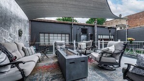 Een moderne zithoek buiten, met een bank, stoelen en een bijzettafeltje.