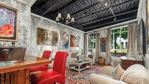 Een kamer met een rustiek industriële plafond, een houten bar, een kamerbreed tapijt met patroon en een bank met kussens.