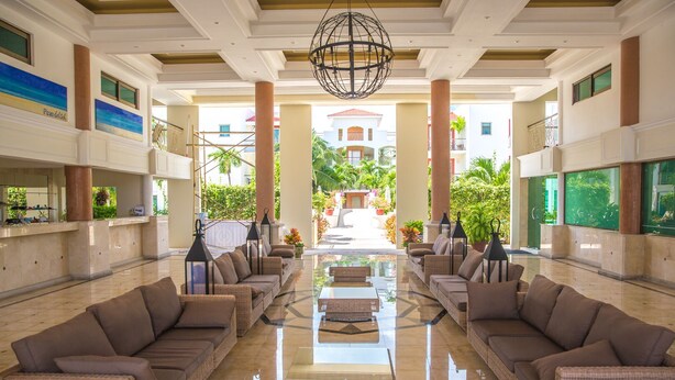 A spacious lobby with a central glass coffee table, comfortable seating, and a view of the outdoor garden. - Spacious, quiet and safe condo one block from the beach in Playacar (Playa del Carmen)