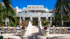 A resort with a pool area, lounge chairs, and potted plants. - Spacious, quiet and safe condo one block from the beach in Playacar (Playa del Carmen)