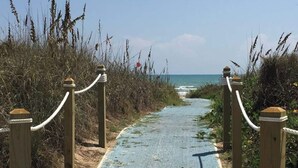 A wooden pathway leading to a beach with a rope barrier on either side. - 2300 sq ft Beach close, spacious 5 star townhome, garage and parking! (South Padre Island)