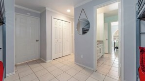 A hallway with a white door, a mirror, and a view into a room with a bed and a window. - 2300 sq ft Beach close, spacious 5 star townhome, garage and parking! (South Padre Island)