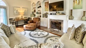 A spacious living room with a fireplace, a comfortable sofa set, a wooden coffee table, and a bookshelf filled with decorative items. - Your Creekside Villa Experience: Relax and Refresh. Brookhill Ranch Area!  (Hot Springs Village)