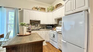 A kitchen with white cabinets, a wooden table, a white refrigerator, and a microwave. - Your Creekside Villa Experience: Relax and Refresh. Brookhill Ranch Area!  (Hot Springs Village)