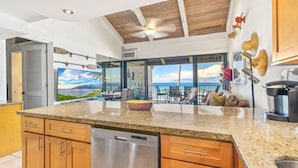A kitchen with a large island, wooden cabinets, and a dishwasher.