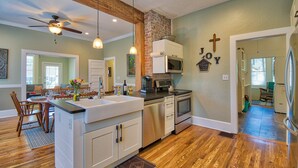 A modern kitchen with a central island, stainless steel appliances, and a brick accent wall. - Bramley House: 3 Blk. Walk to DWTN Hendersonville-Lovingly Restored (Hendersonville)