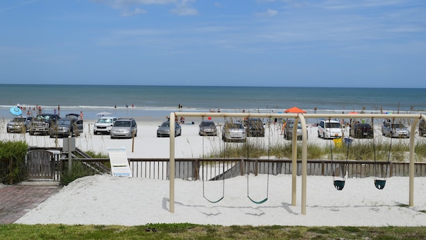 Une plage dotée d’un parking, d’une aire de jeux avec des balançoires et offrant une vue sur l’océan.