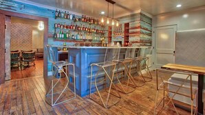 A bar area with wooden flooring, metal bar stools, and a wall of liquor bottles. - Walk to the Beach and Downtown Restaurants, Bars, and Shops! (Ocean Springs)