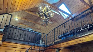Ein Holzhütten-Interieur mit einer Treppe, einem Chandelier und einem Oberlicht.