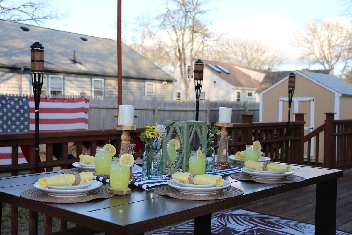 A dining table set outdoors with a flag, candles, and drinks.