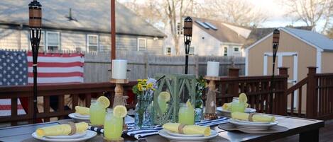 A dining table set outdoors with a flag, candles, and drinks.