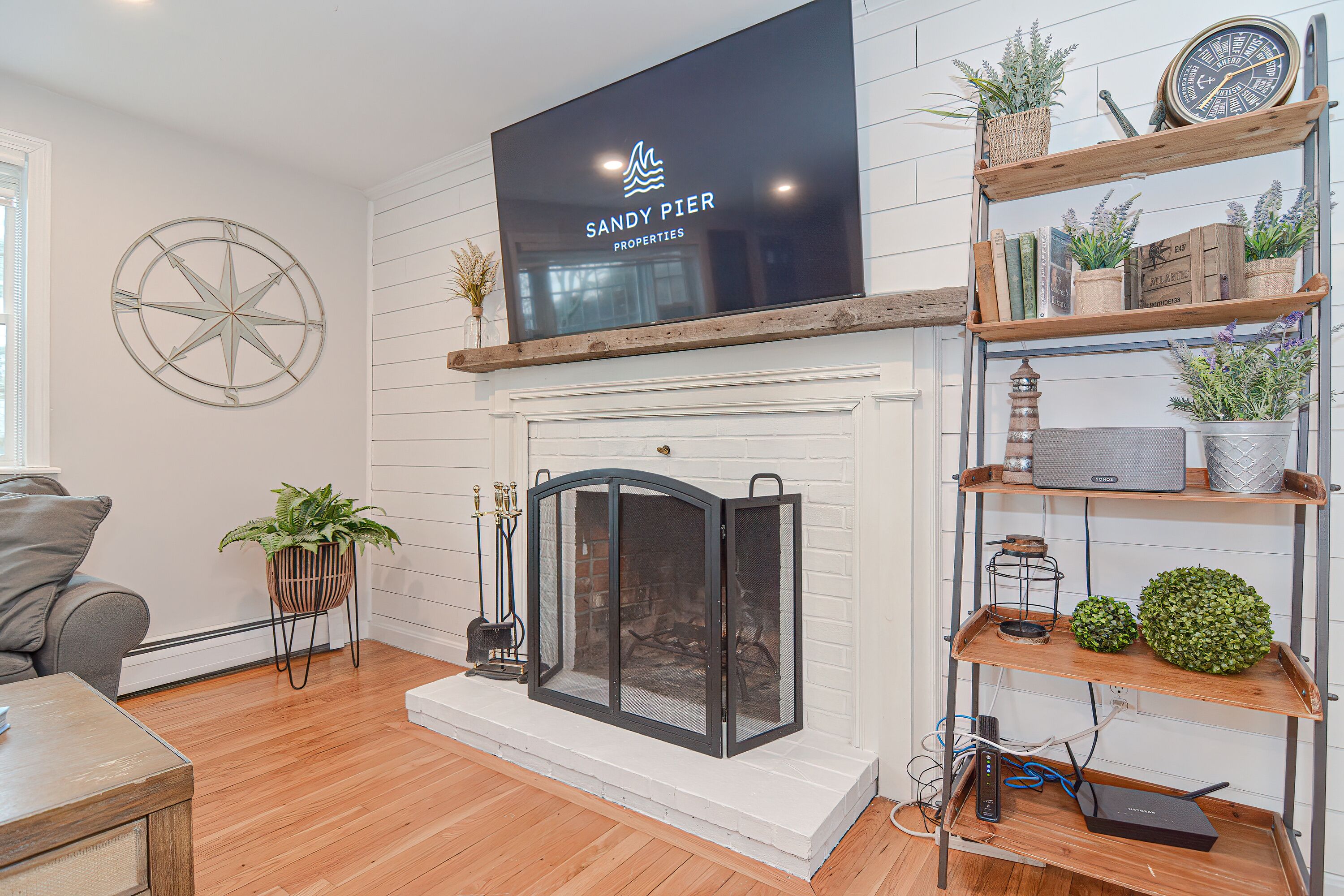 Una sala de estar con chimenea, un televisor montado y estantes de madera con plantas.