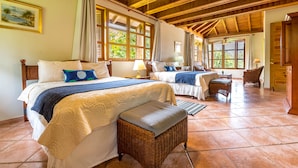 A spacious room with two beds, a wicker bench, and a wooden ceiling.