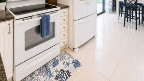 Une cuisine moderne avec des meubles blancs, un four à micro-ondes encastré, une cuisinière et un réfrigérateur.