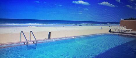 Piscina com vista para a praia e o oceano.