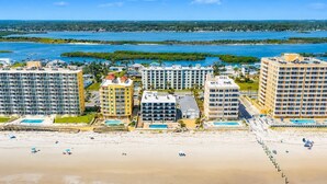 Un hôtel situé sur la côte, composé de plusieurs bâtiments, avec une plage et une vue sur l’océan.