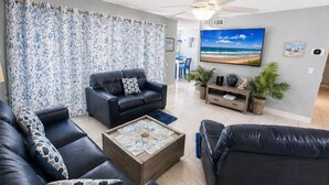 Un salon avec un canapé, une table basse et un téléviseur fixé au mur.