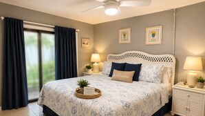 Une chambre à coucher avec un lit, des tables de chevet, un ventilateur de plafond et une vue sur l’extérieur.