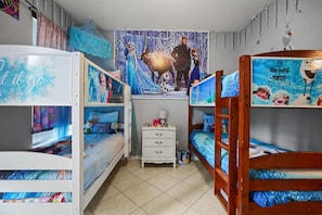 A child's bedroom with bunk beds, a poster of Frozen characters, and a small dresser.