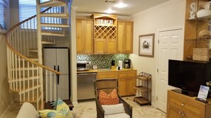 Cozy living space with a central kitchen area, featuring a spiral staircase and a functional design.