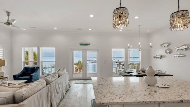 Una cocina amplia con una isla grande, armarios blancos y vistas al agua.