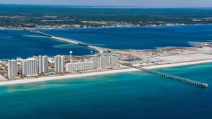 Un complejo turístico costero con varios edificios altos, un muelle largo que se adentra en el mar y una zona de playa.