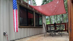 A covered outdoor area with a wooden deck, a table with chairs, and an American flag. - Fallen Leaf Lake is Widely Considered the Most Scenic Place around Lake Tahoe (South Lake Tahoe)