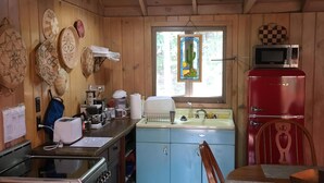 A compact kitchen with wooden walls, a stove, a sink, and a microwave. - Fallen Leaf Lake is Widely Considered the Most Scenic Place around Lake Tahoe (South Lake Tahoe)