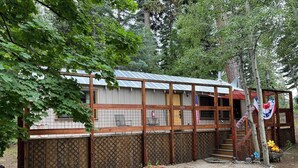 A rustic cabin with a metal roof, wooden deck, and a fenced area. - Fallen Leaf Lake is Widely Considered the Most Scenic Place around Lake Tahoe (South Lake Tahoe)