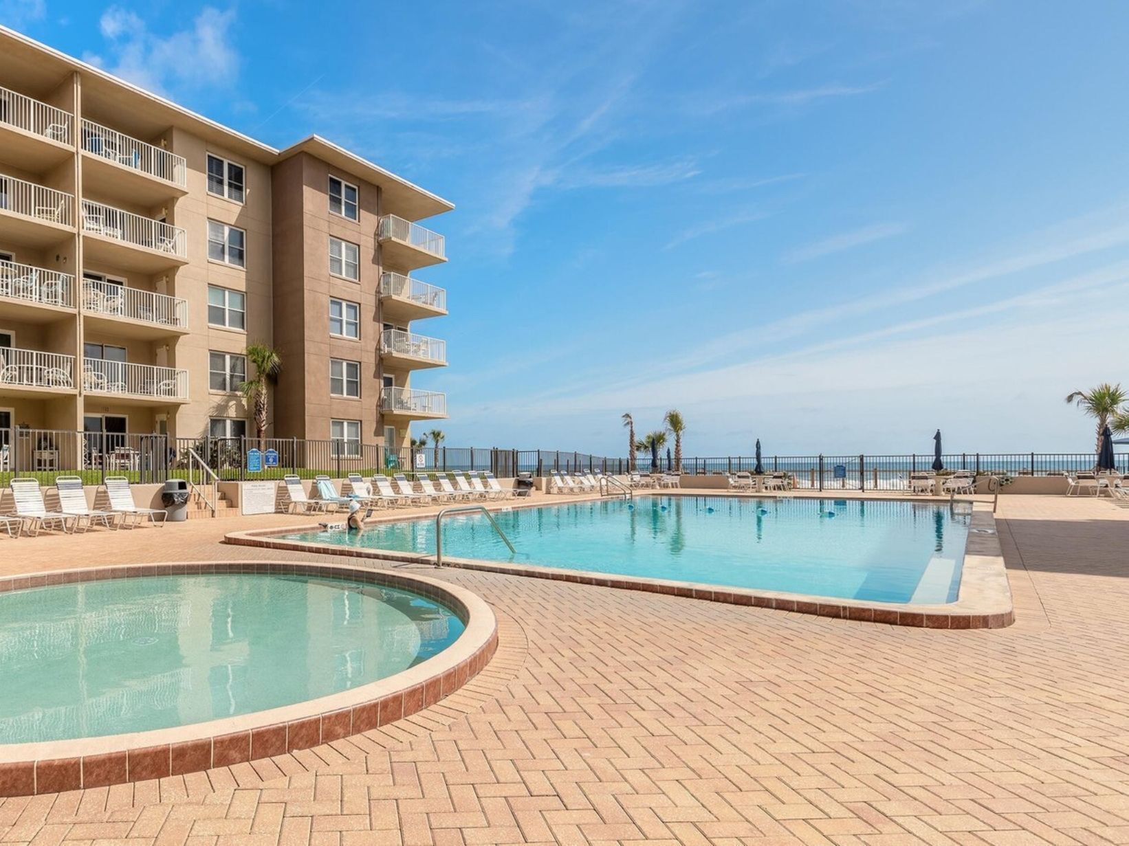 A hotel with a pool area, multiple balconies, and a view of the ocean.