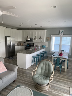 Una cocina moderna con armarios blancos, una isla central y taburetes de bar color turquesa.