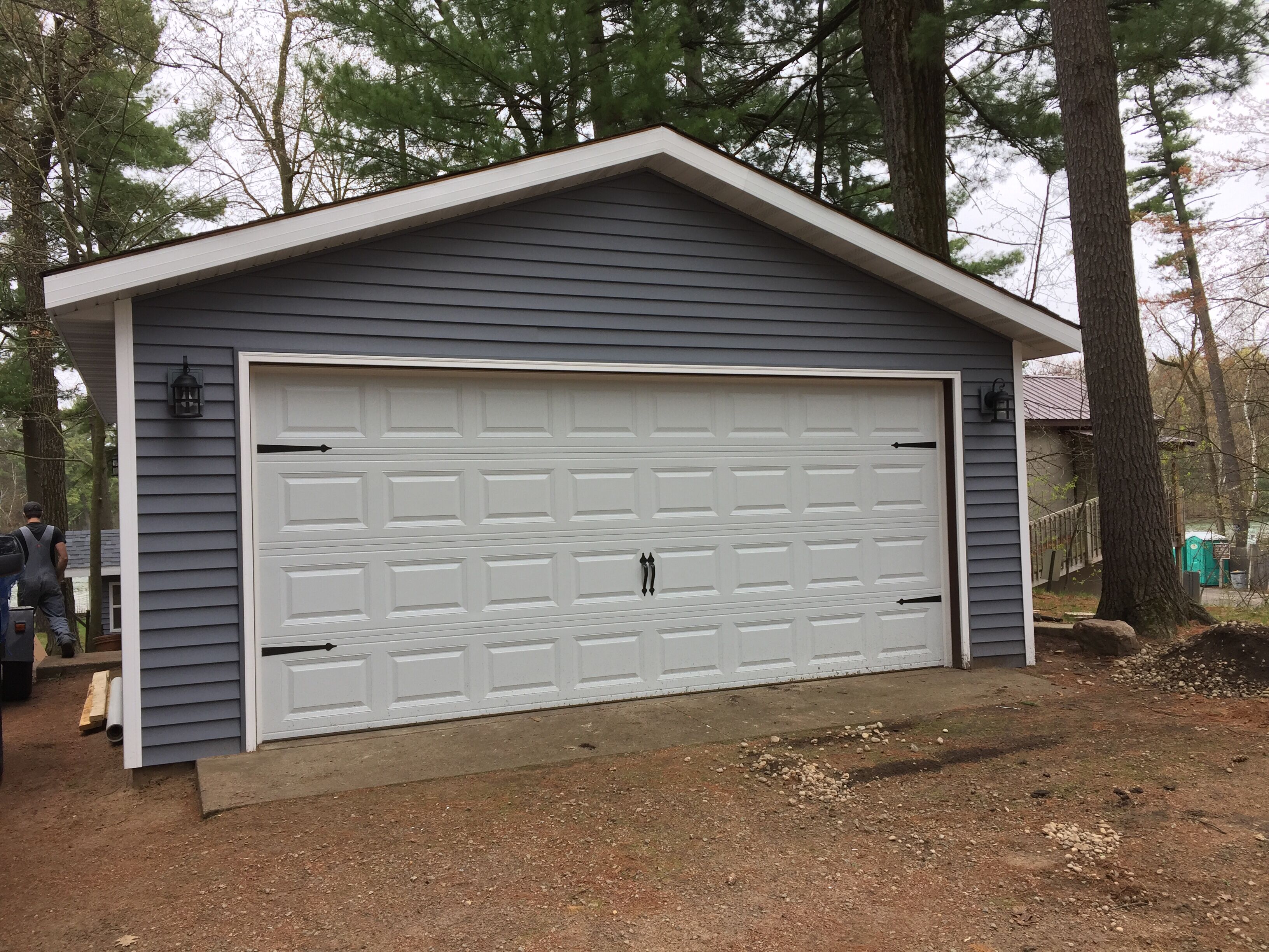 A garage with a white door, grey siding, and a small porch area.